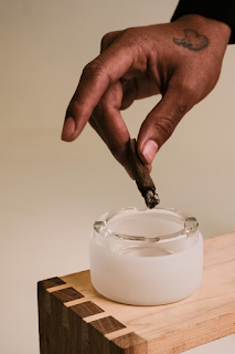 Close-up of a person holding a blunt over an ashtray for a beginner blunt rolling guide